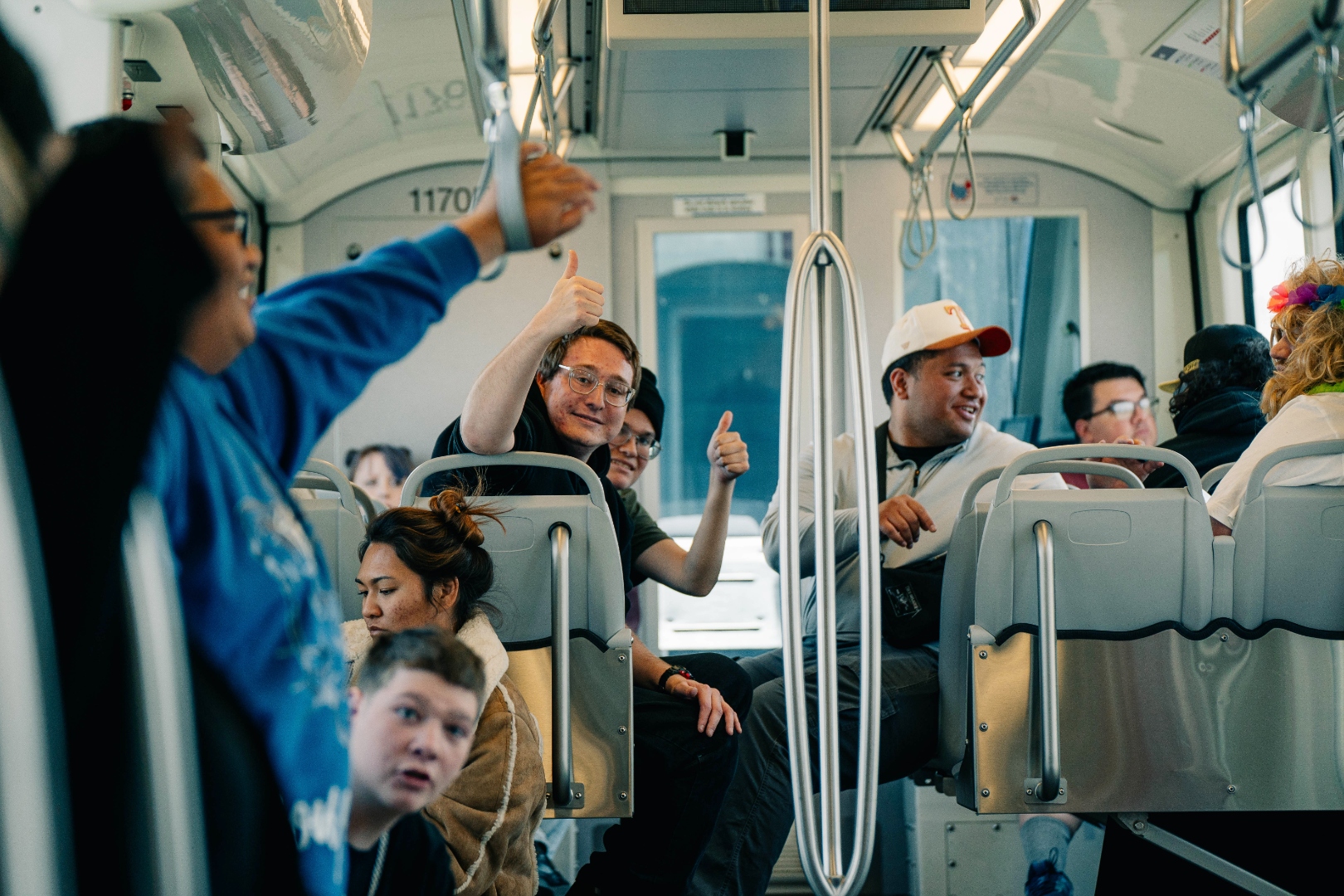 FaleOfaz clients and staff riding the TRAX train together, thumbs up and smiling